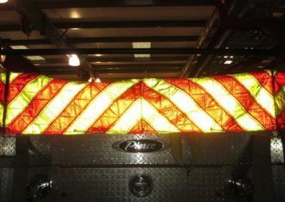 Red and yellow chevron-patterned illuminated panel above a dark metal surface