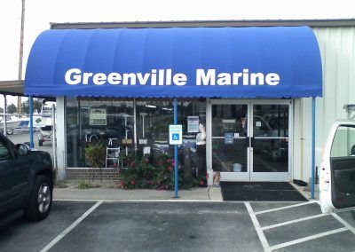 Greenville Marine storefront with blue awning and glass entrance, viewed from the parking lot