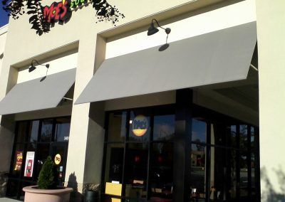 Storefront with gray awnings and glass doors on a sunny day