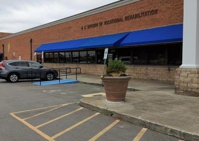 Storefront with blue awning and accessible parking space in front of a brick building