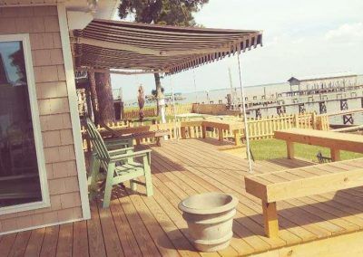 Wooden deck with benches and pergola overlooking a sunny waterfront marina