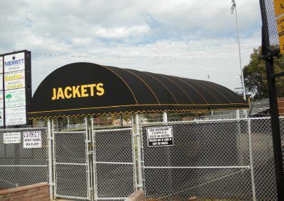 Black awning labeled “JACKETS” over a fenced outdoor area at a sports field