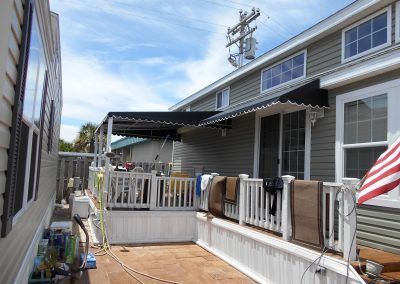 Backyard deck beside a house, with white railings, a covered patio, and an American flag.