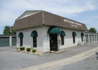 Small white building with green awnings and a shingled roof, labeled as a pet wash station.