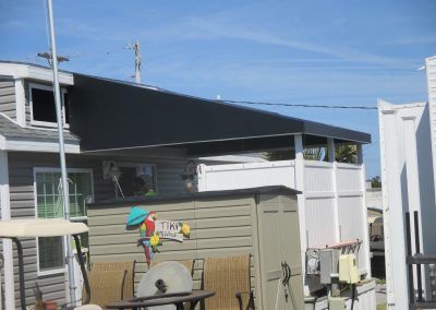Backyard with a covered patio, beige shed, and colorful pinwheel under a blue sky