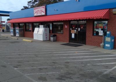 Convenience store storefront with blue facade, red awning, and parking lot in front