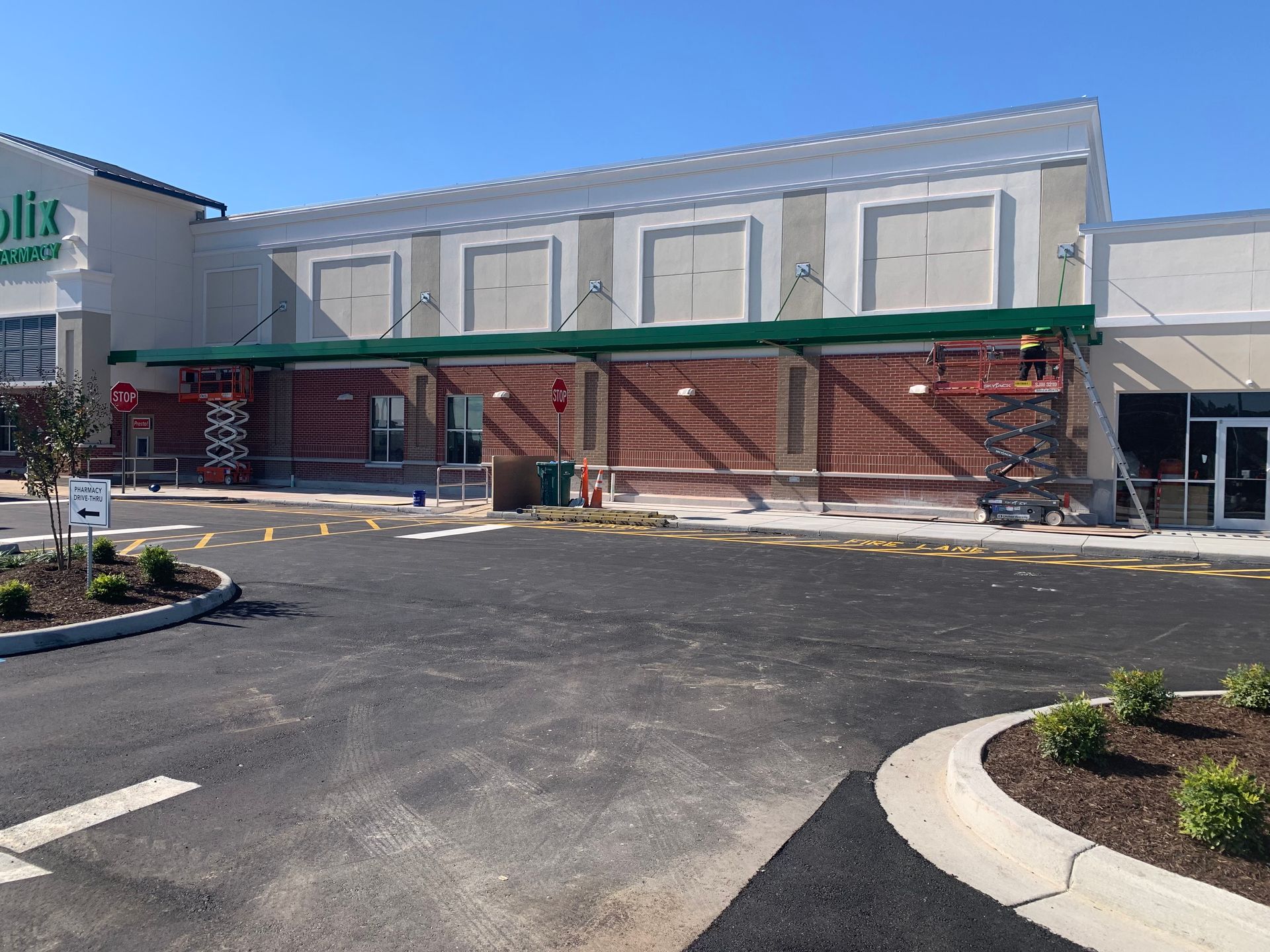 Storefront under construction with green scaffolding and a parking lot in front