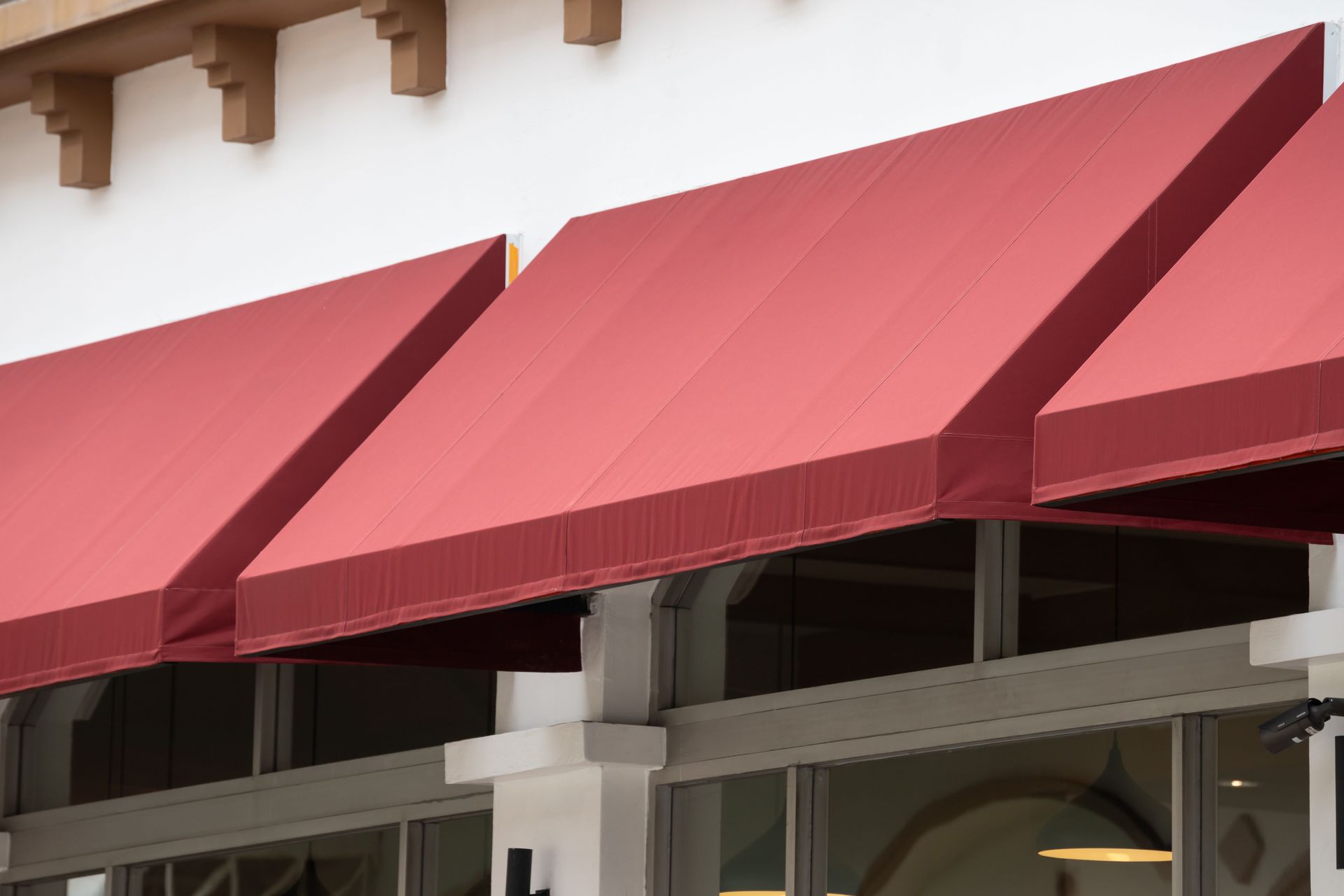 Red awnings over storefront windows on a building exterior