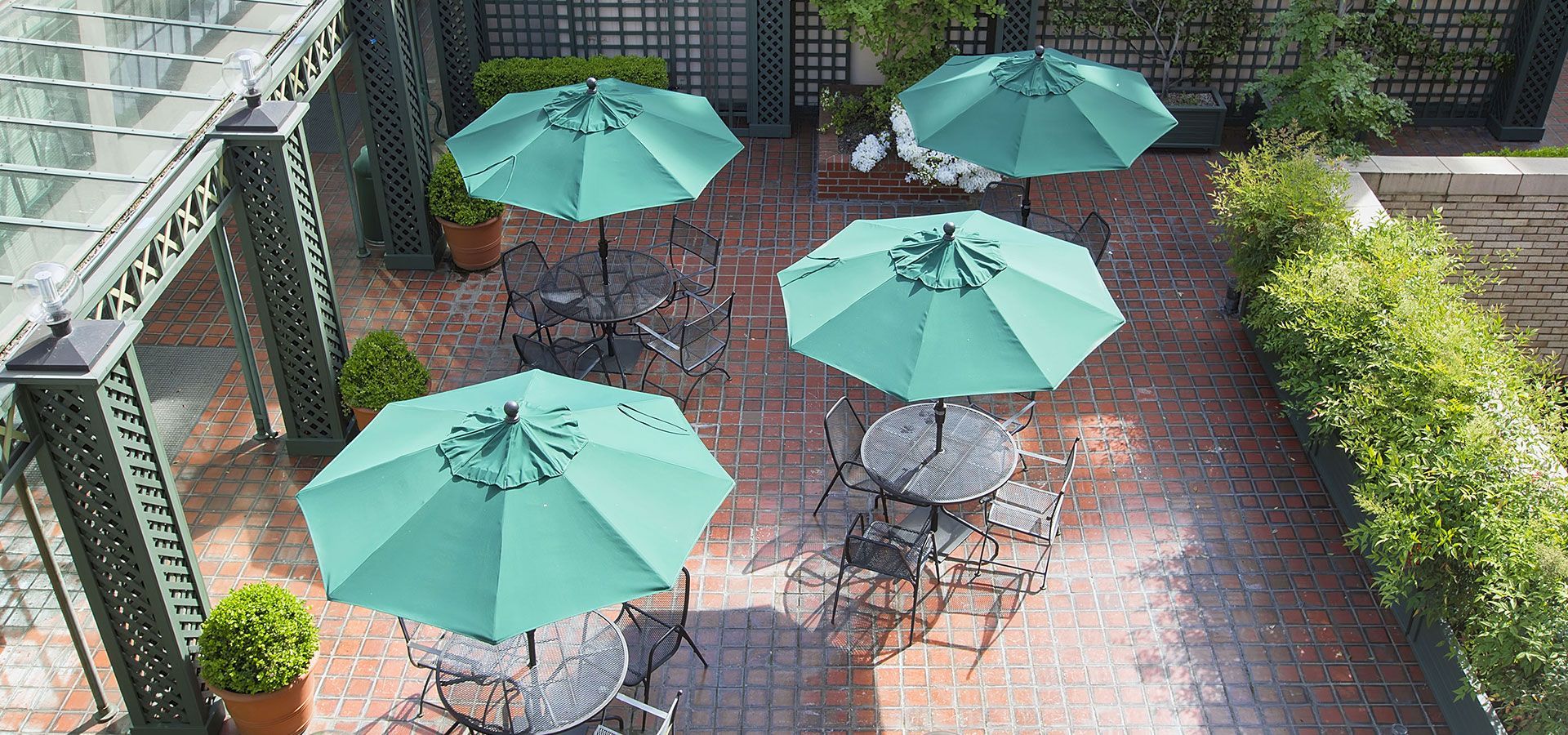 Outdoor patio with mint-green umbrellas and metal tables on a brick courtyard