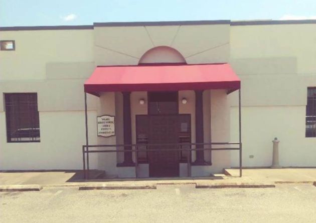 Front entrance of a building with a red awning and ramp, viewed from the street.