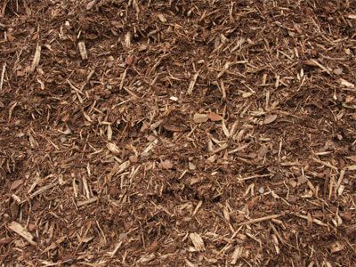 A pile of brown mulch is sitting on the ground.