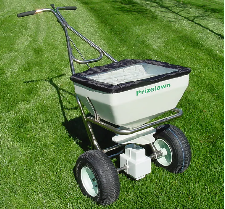 A wheelbarrow filled with fertilizer is sitting on top of a lush green lawn.
