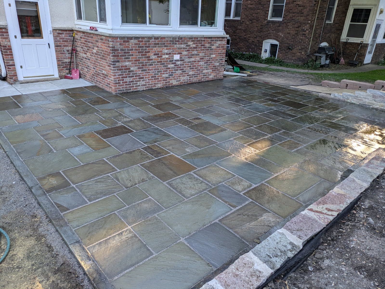 A stone patio is being built in front of a brick house.