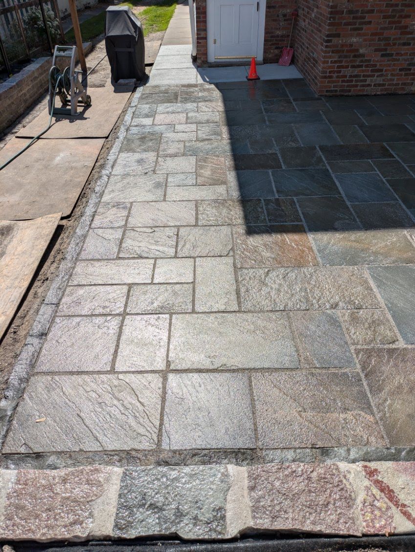 A stone walkway is being built in front of a brick house.