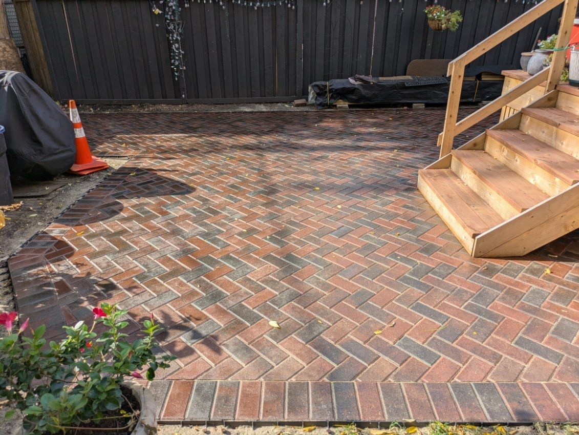 A brick patio with stairs and a fence in the background.