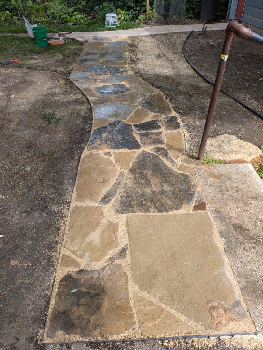 A stone walkway is being built in a backyard.
