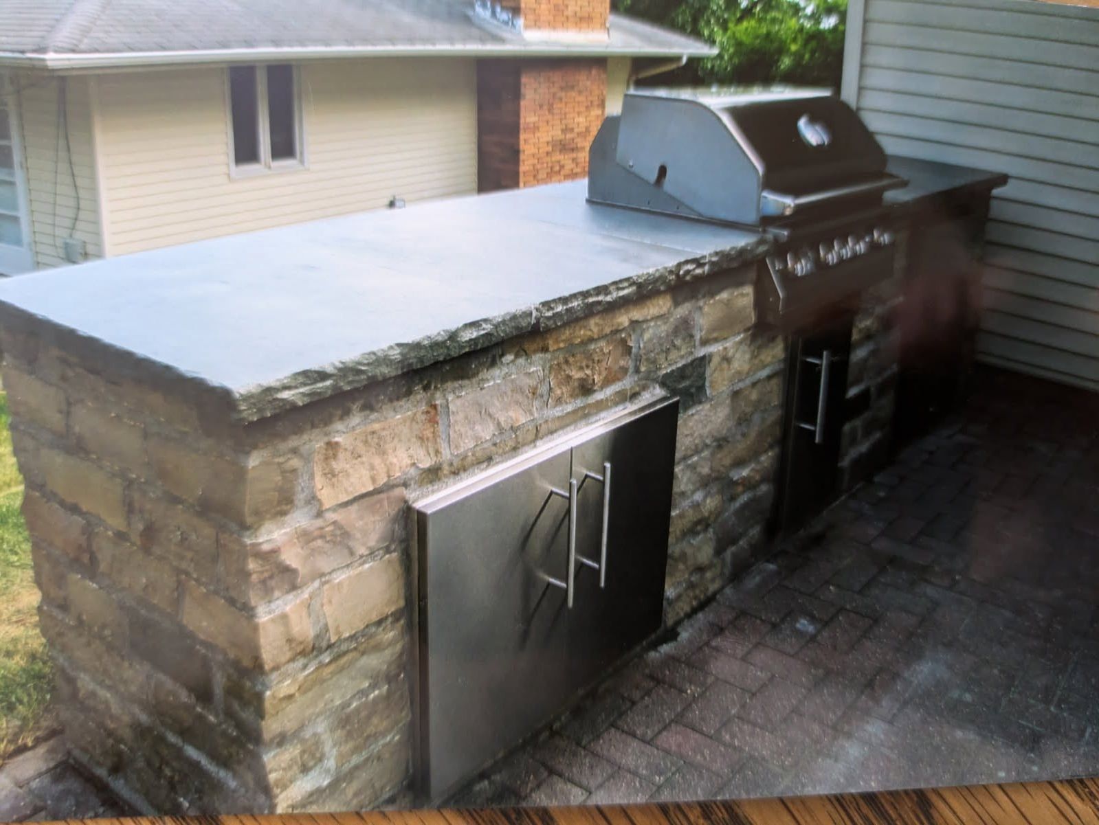 A picture of an outdoor kitchen with a grill on top of it