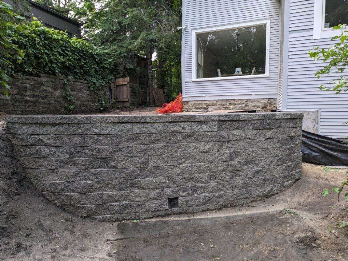 A brick wall is being built in the backyard of a house.