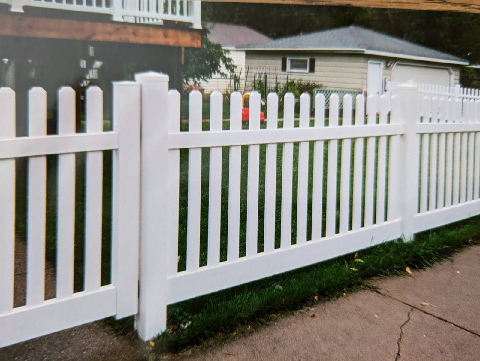 A white picket fence is in front of a house