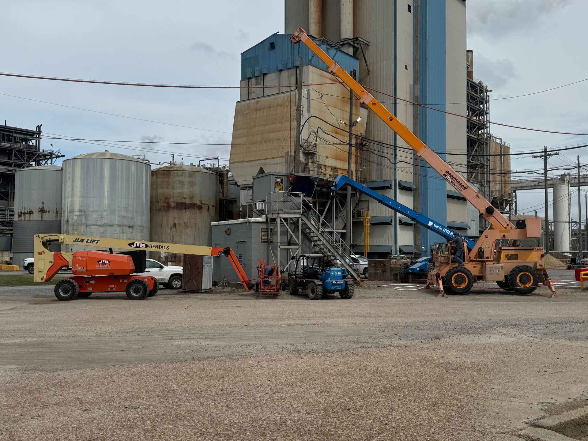 Construction site: Buildings and industrial tanks with cranes and machinery. Overcast sky.
