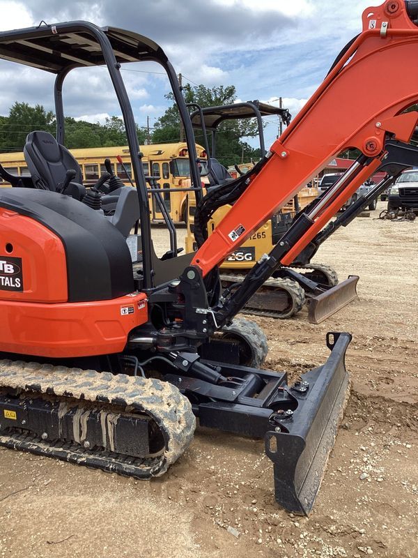 Orange Kubota excavator with black tracks and blade, parked on dirt.
