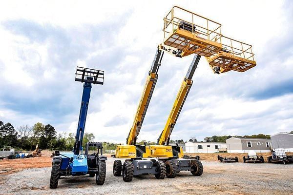 Three aerial lifts on a construction site; one blue, two yellow with raised platforms, outdoors.