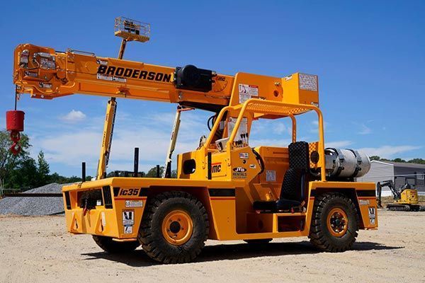 Yellow Broderson crane on wheels at a construction site.