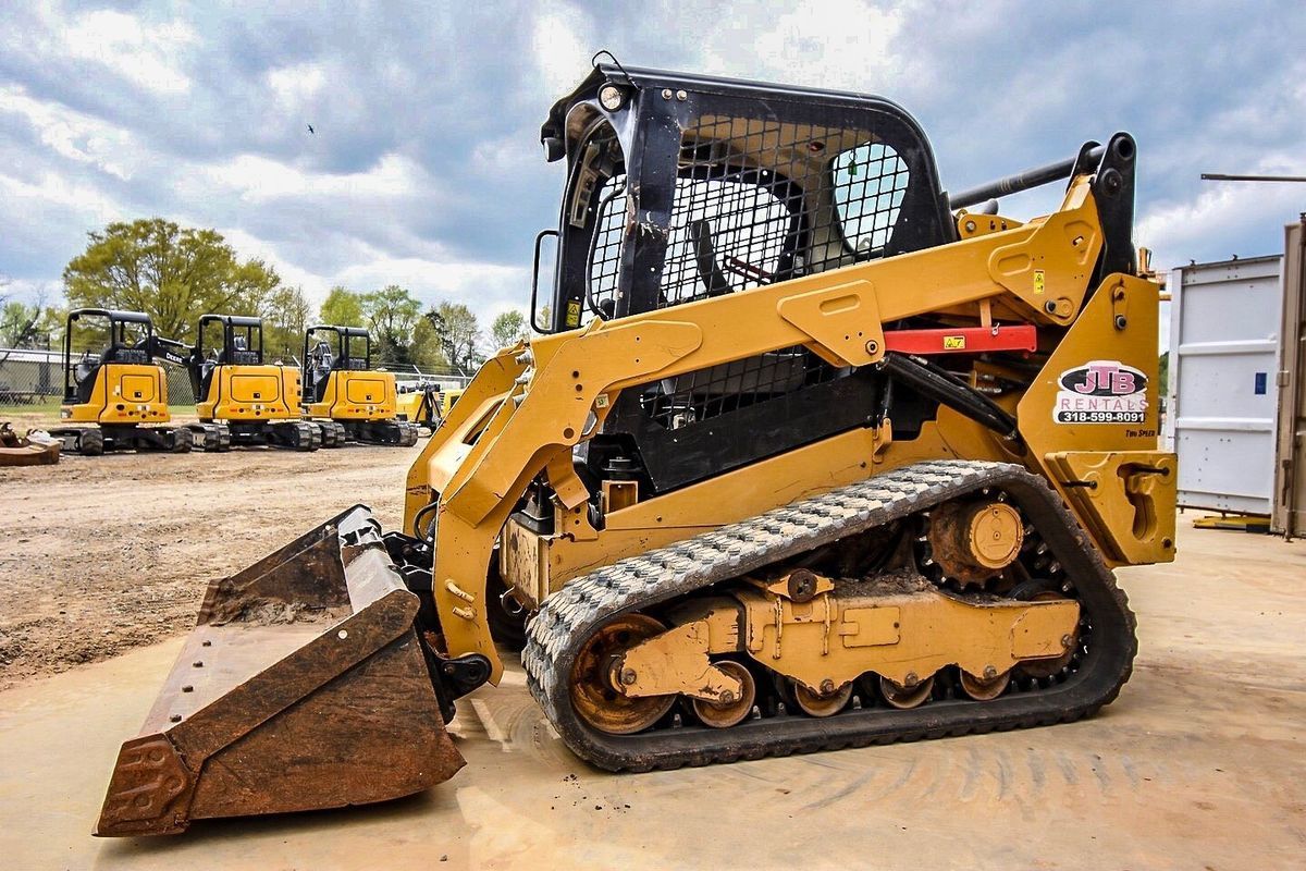 Yellow track loader with a bucket, parked outdoors.
