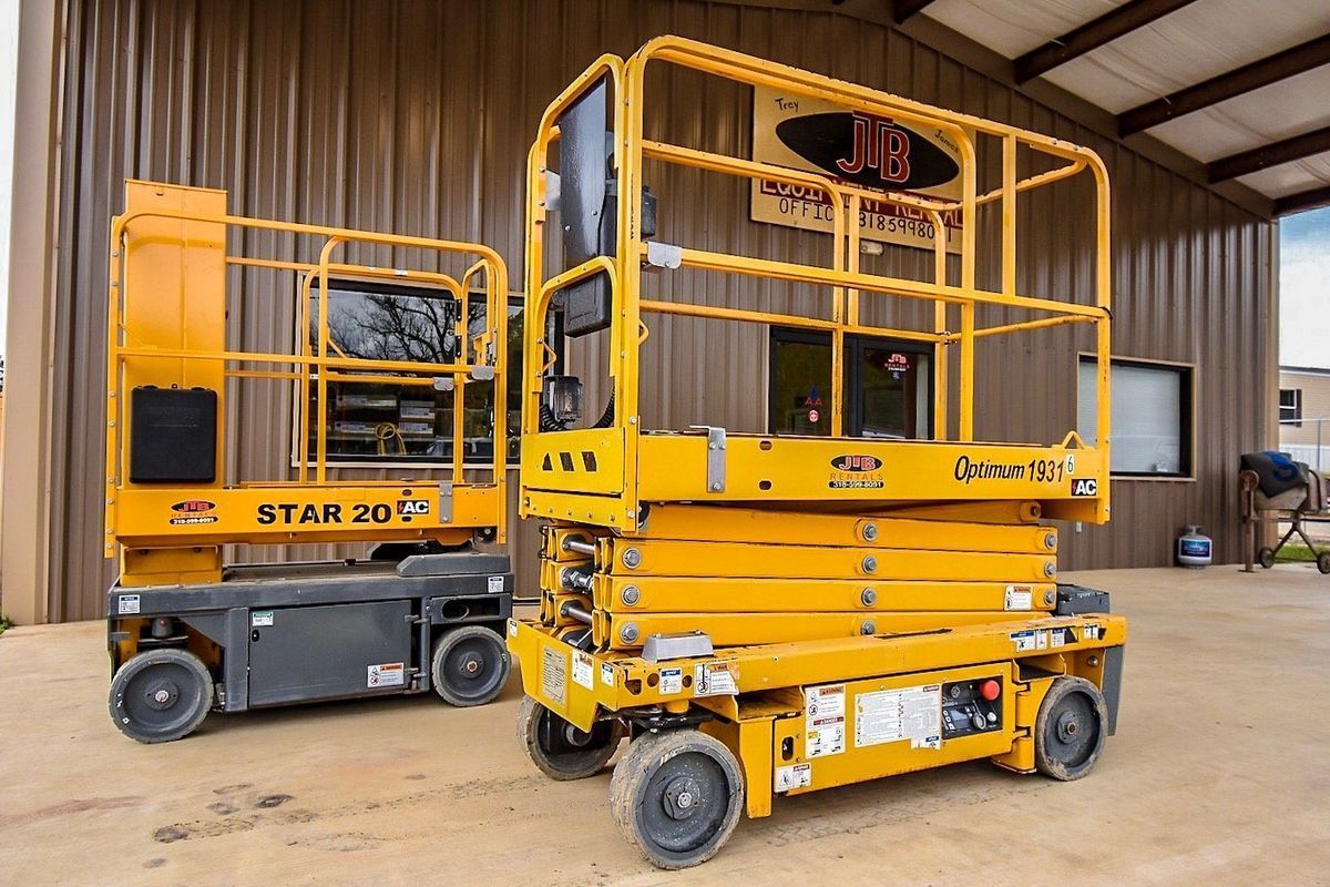 Two yellow scissor lifts parked outdoors.
