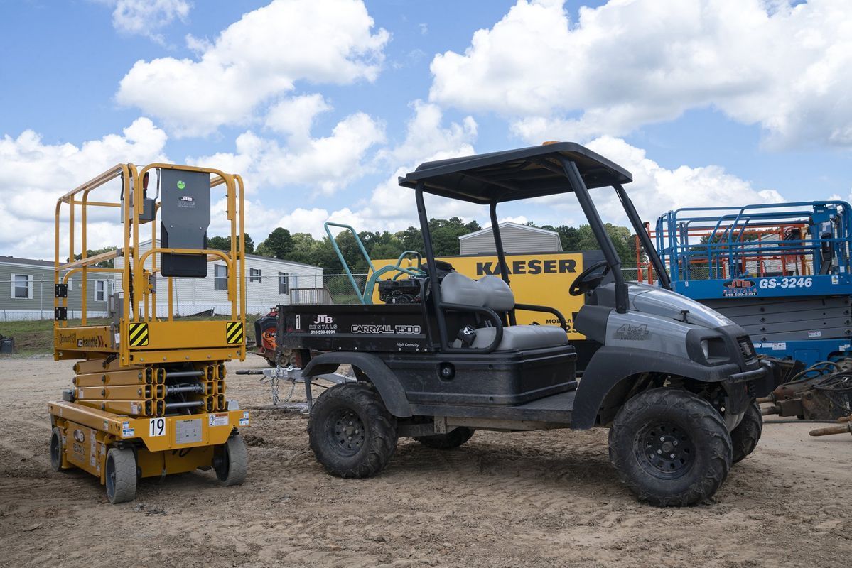 Yellow scissor lift and dark gray utility vehicle on a construction site.