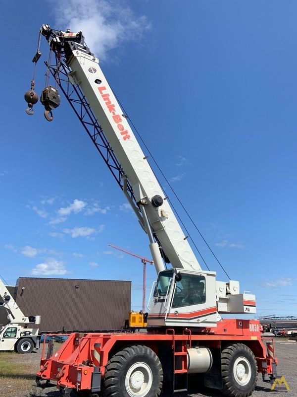 A Link-Belt crane on a red chassis under a blue sky.