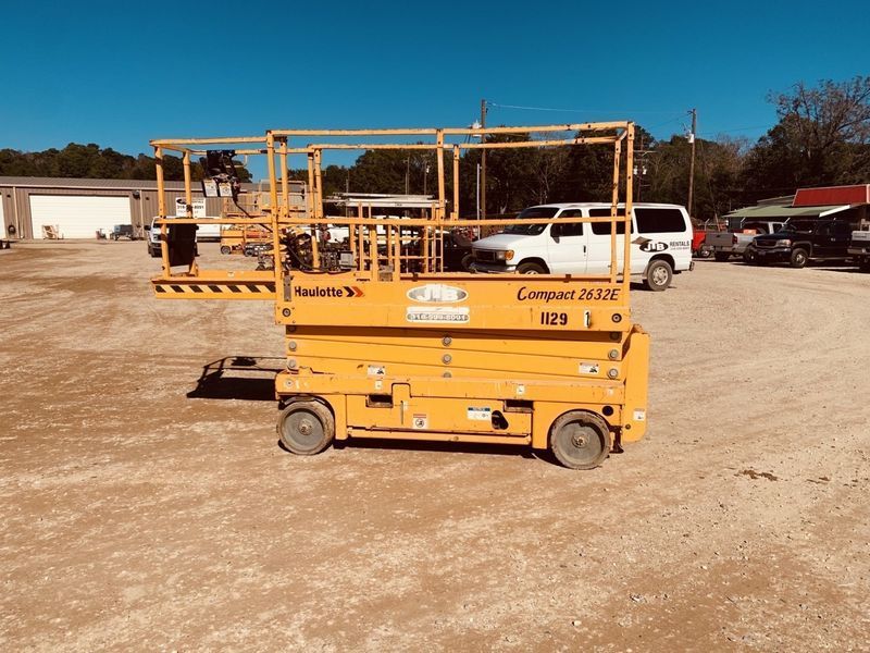 Yellow scissor lift on gravel lot.