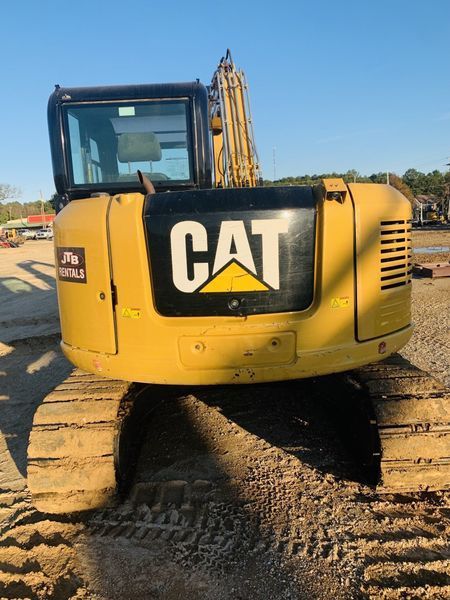 Yellow Caterpillar excavator with black logo, parked outdoors.