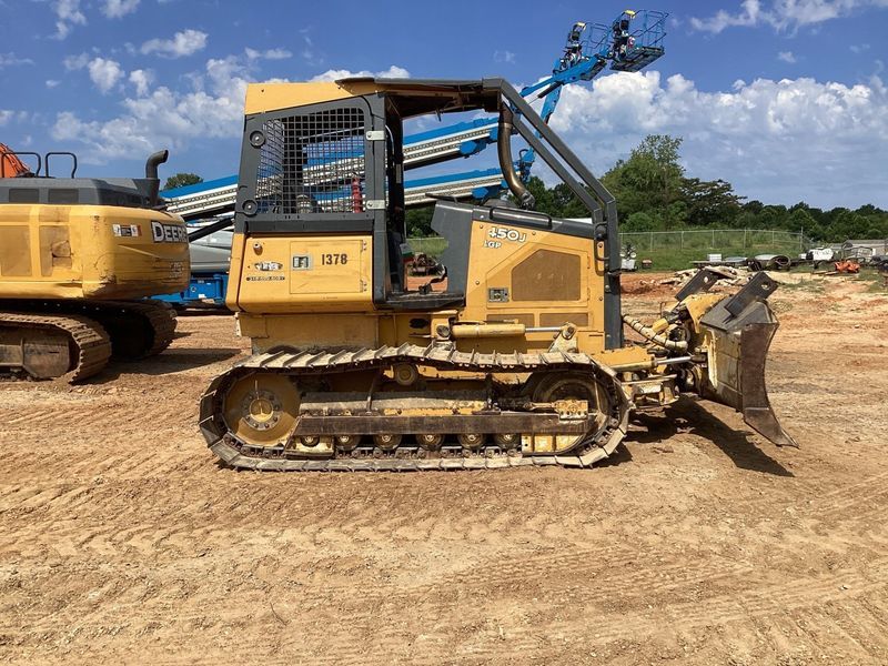 Yellow Case 350 dozer on dirt. Blade forward. Construction equipment in background.