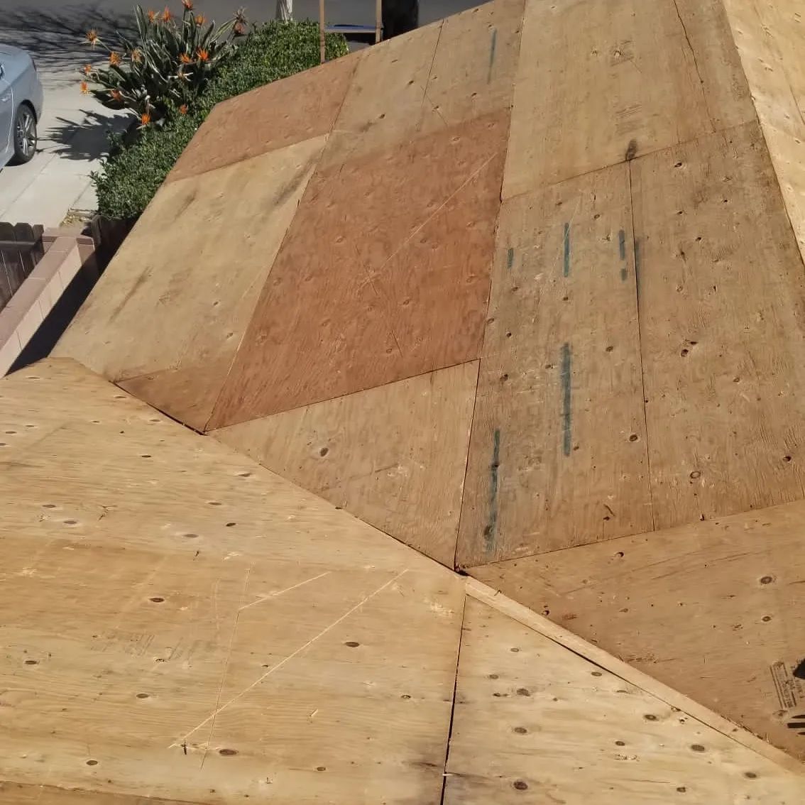 A blue truck with a ladder on the back is parked in front of a house.