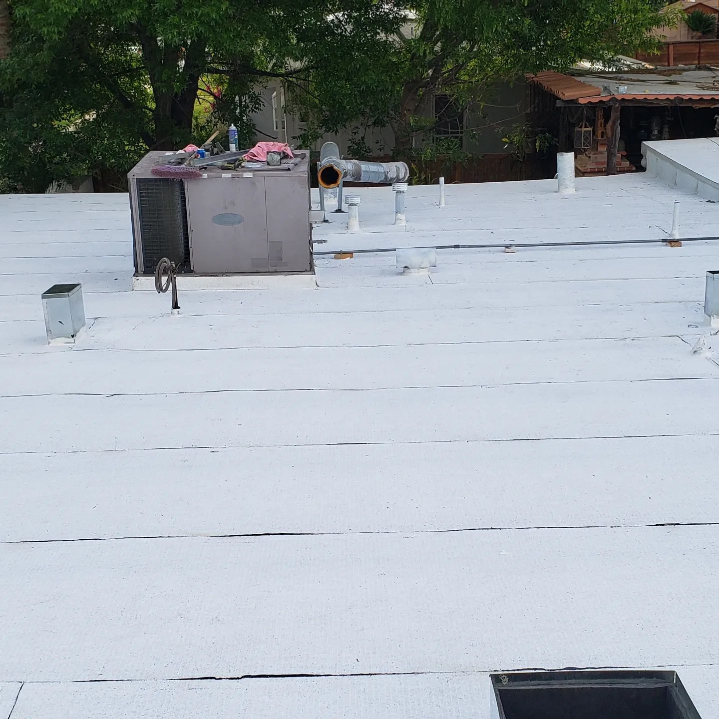 A roof with a lot of shingles on it and trees in the background.