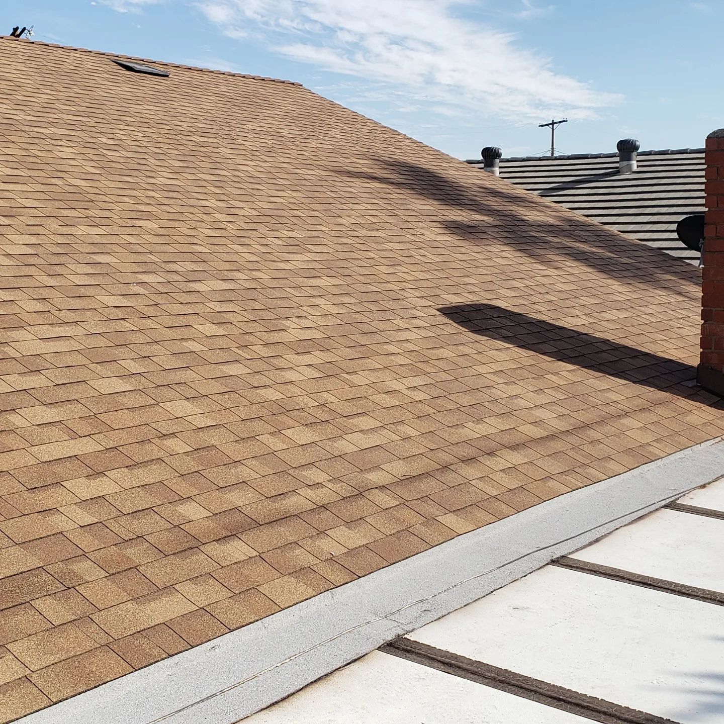 A row of rolls of roofing material are lined up on the ground
