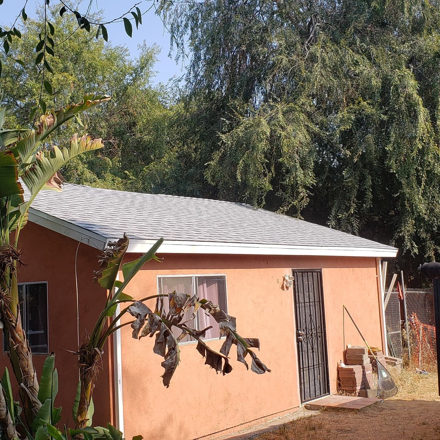 A small orange house with a white roof is surrounded by trees