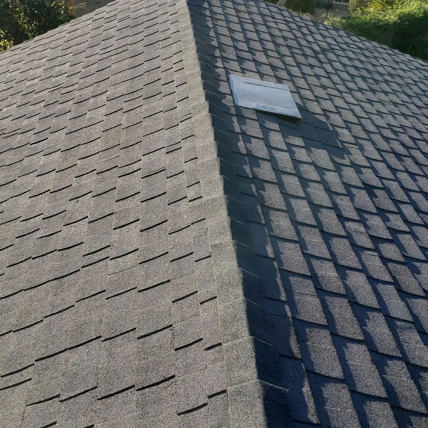 A close up of a roof with shingles and a skylight