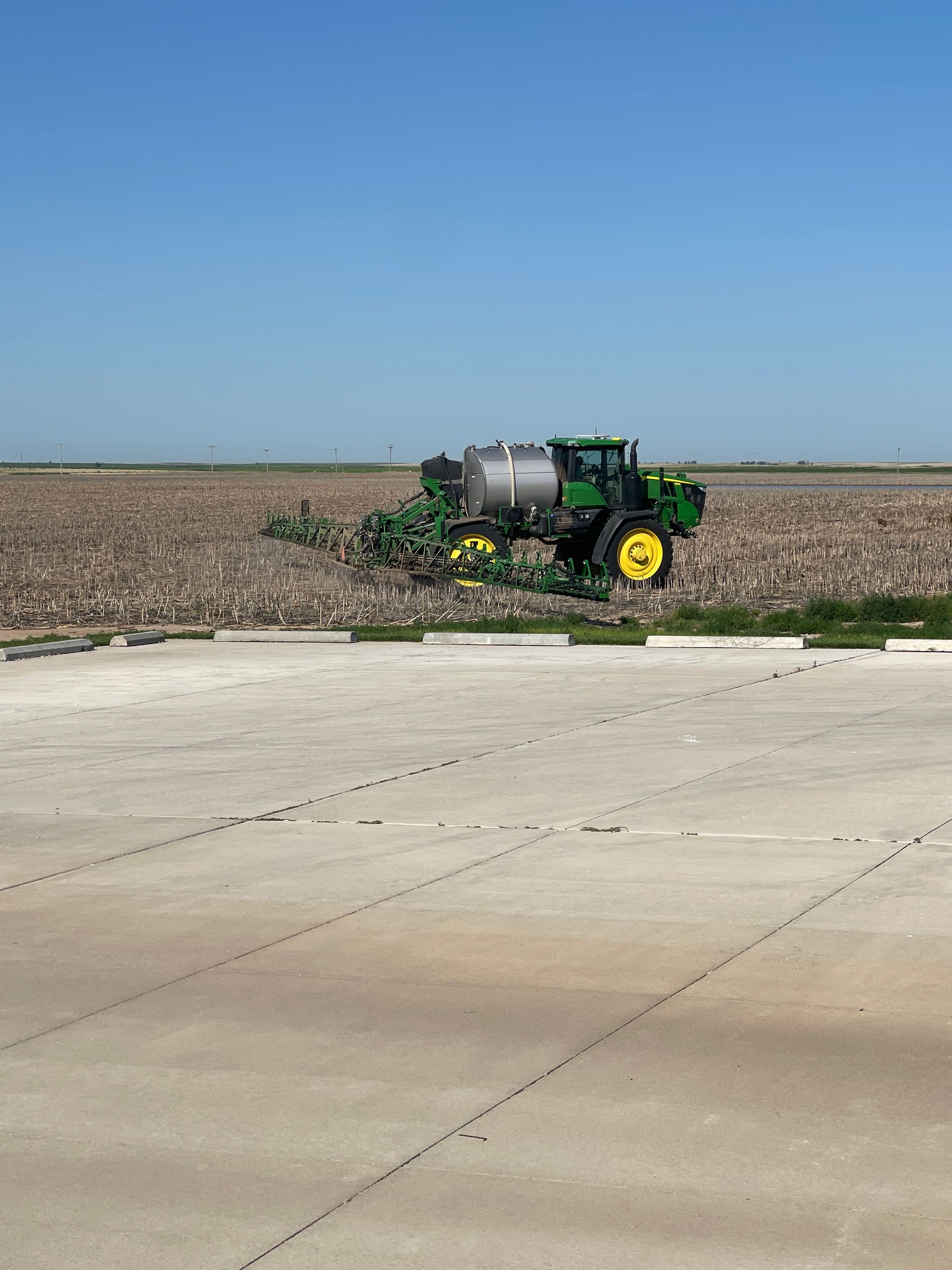 A john deere tractor is plowing a field on a sunny day.