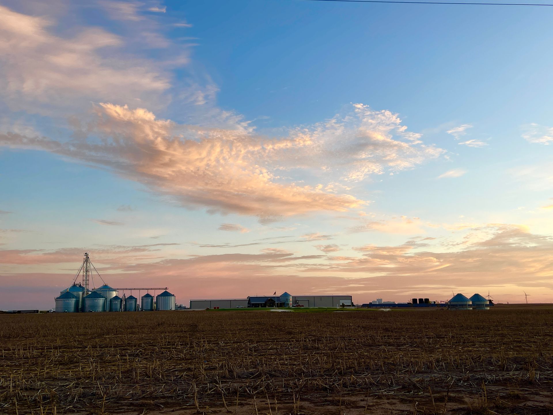 A farm with silos and a sunset sky in the background