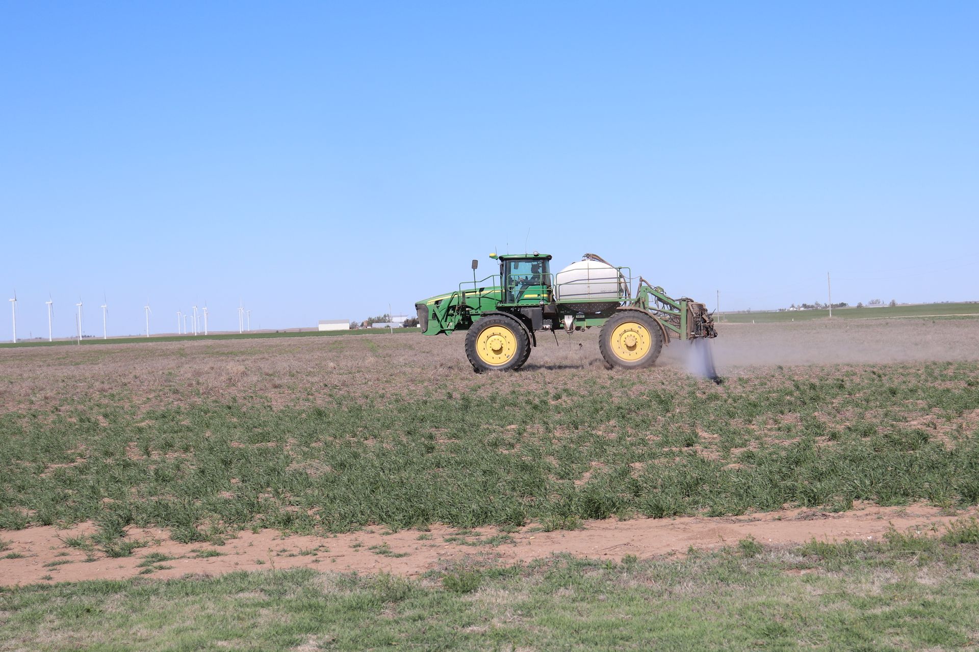 A man is spraying a field with a tractor.