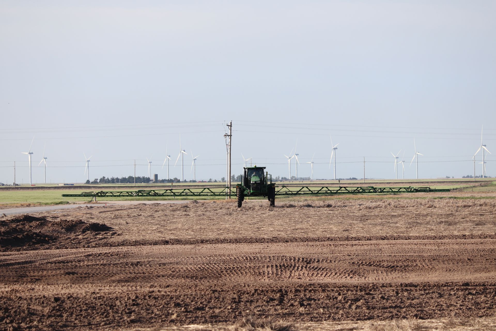 A tractor is spraying a field with a sprayer.