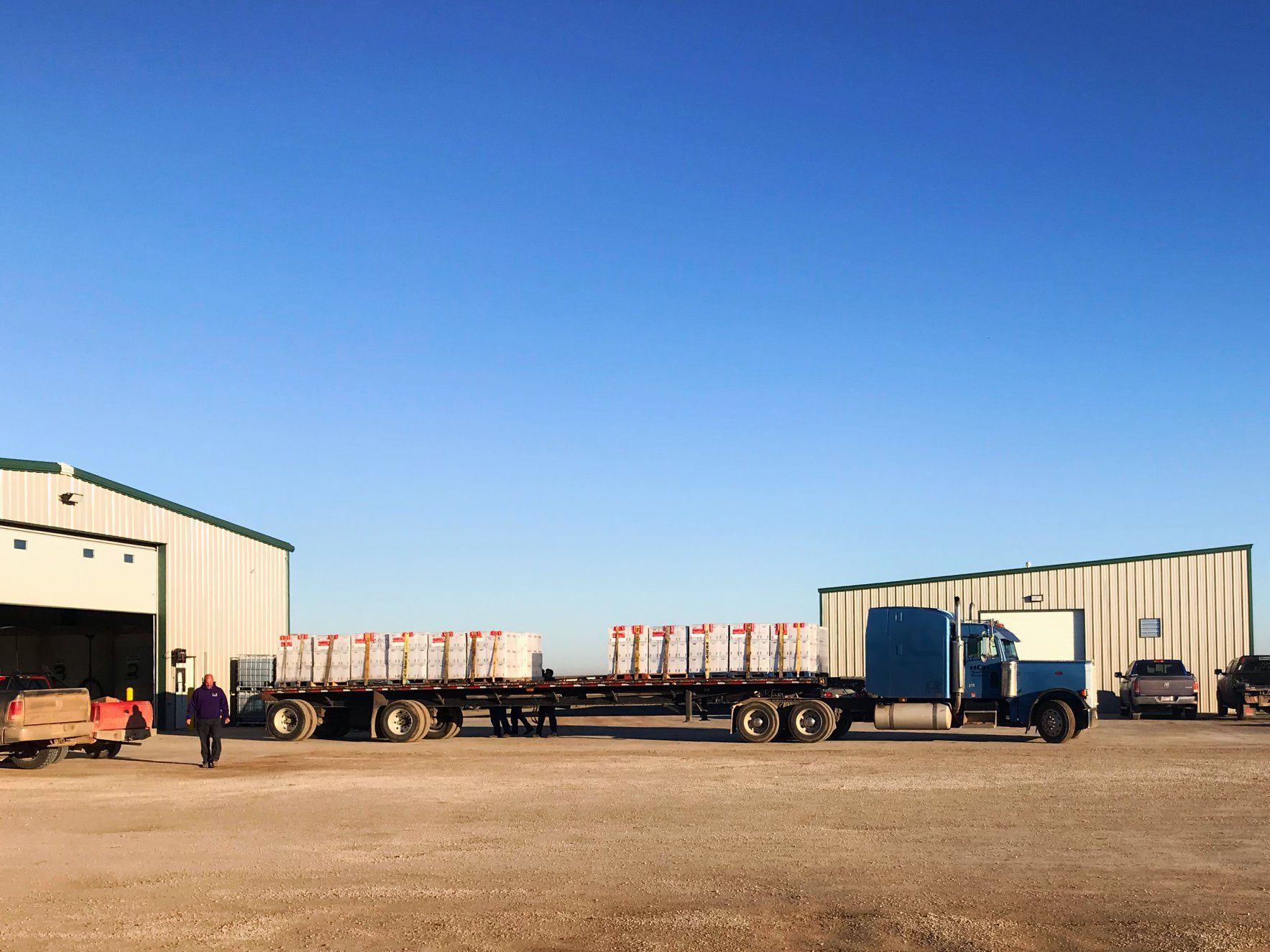 Two semi trucks are parked in front of a building