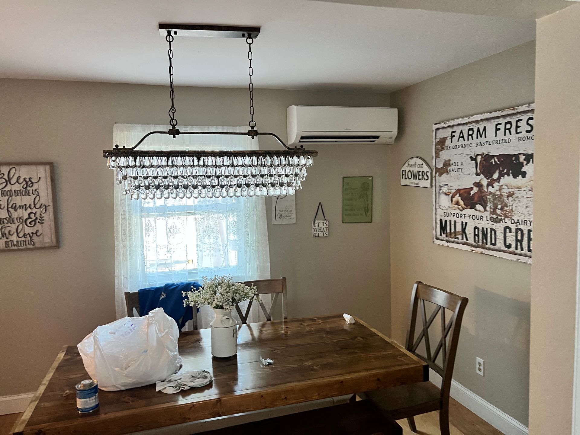 A dining room with a wooden table and chairs and a chandelier hanging from the ceiling.