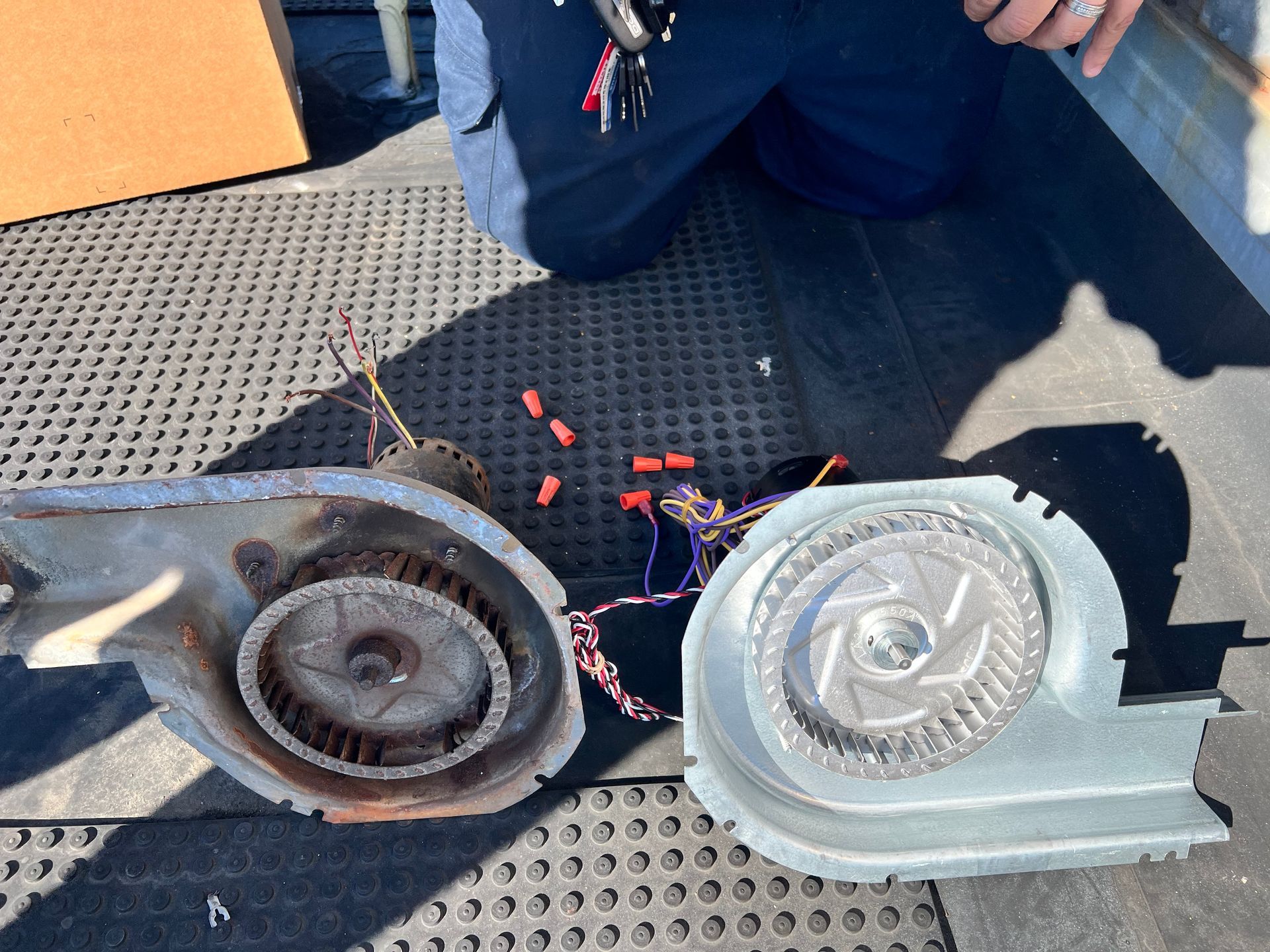 A person is kneeling down next to a pair of blower fans