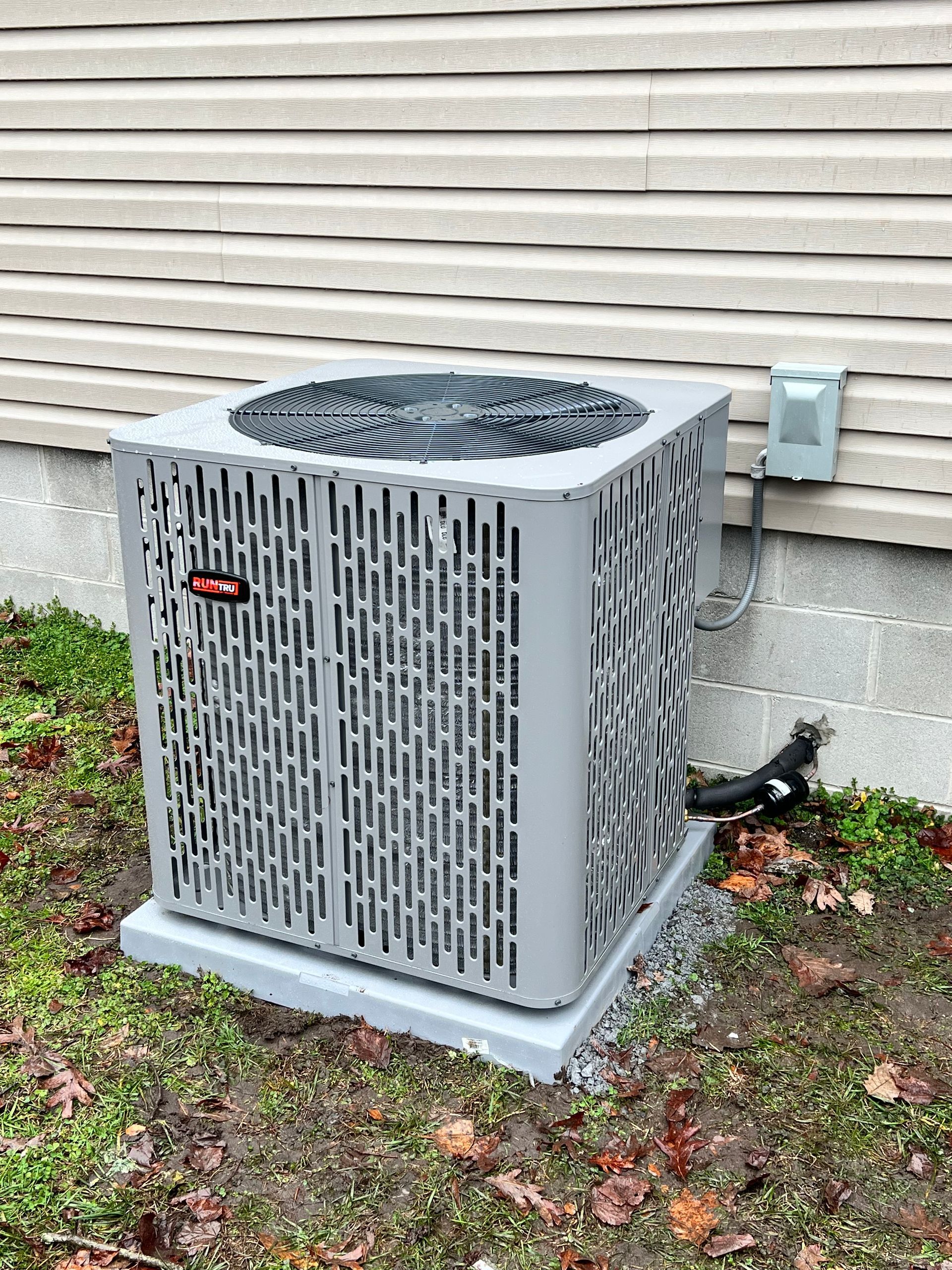 A large air conditioner is sitting outside of a house.
