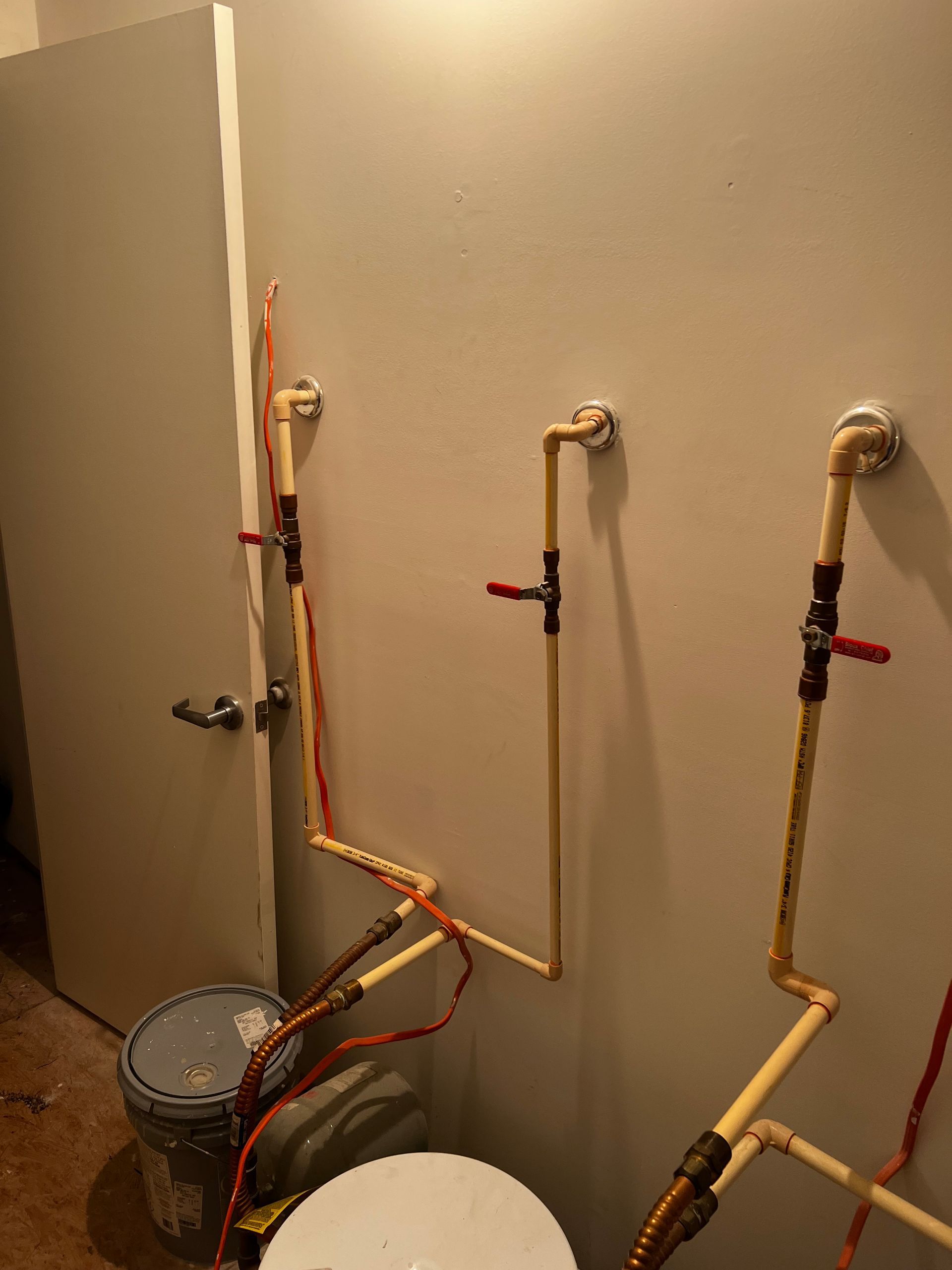 A bathroom with a toilet and pipes on the wall