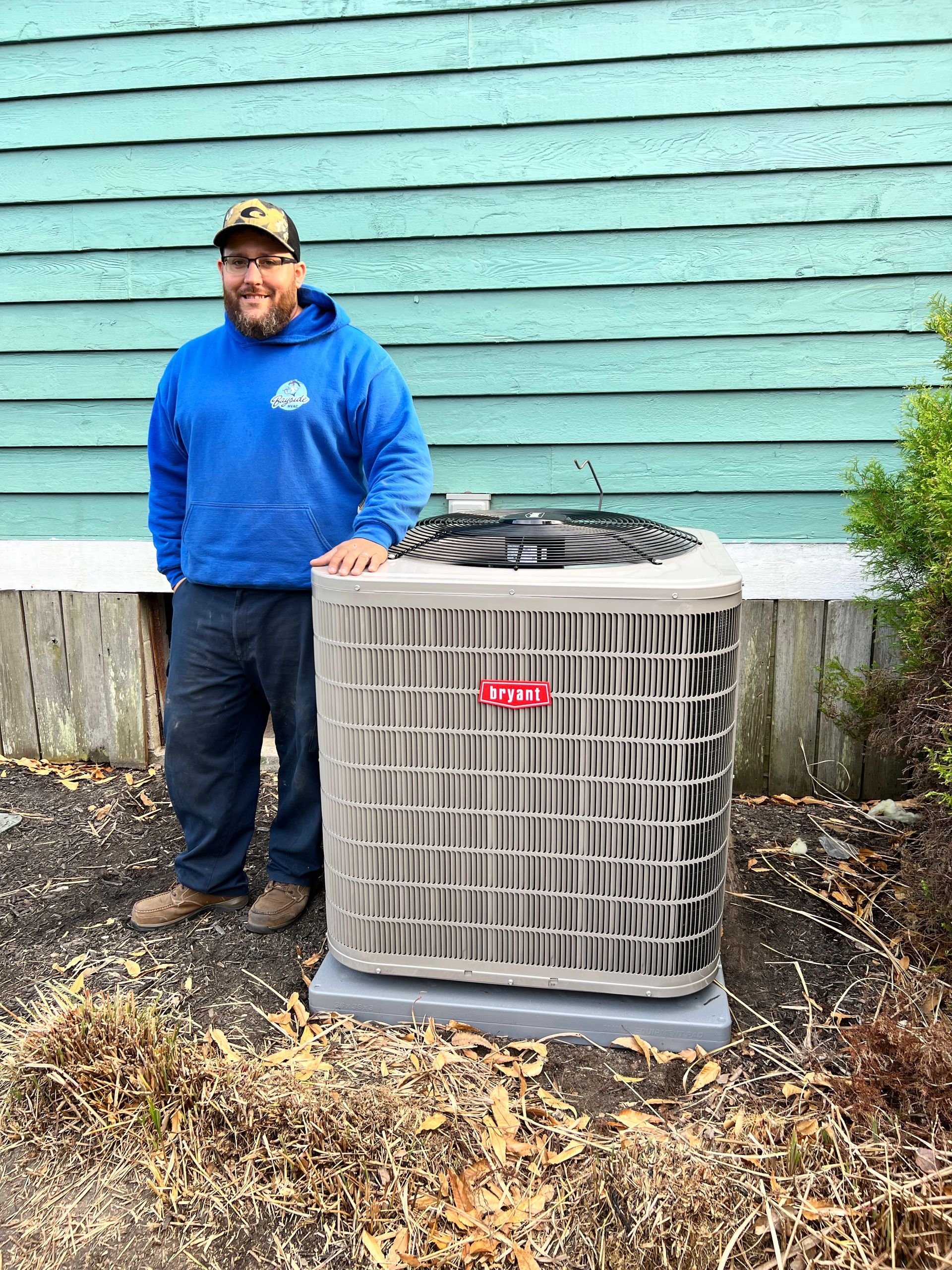 A man is standing next to a large air conditioner outside of a house.