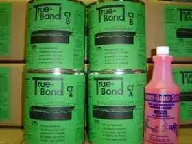 Green True-Bond glue cans stacked beside a pink bottle in a store or workshop setting.